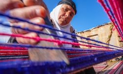Evinin bahçesindeki tezgahta asırlık yöntemle kilim dokuyor